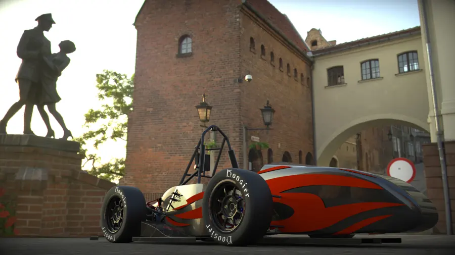 Red and black race car beside a statue